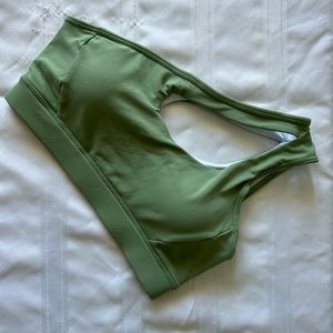 Two green single shoulder sports bras and one red sports bra with low cross back